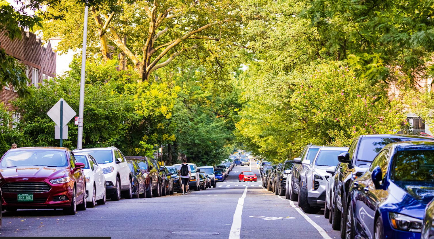 NYC street with cars parked along the side of the road, illustrating urban parking problems.
