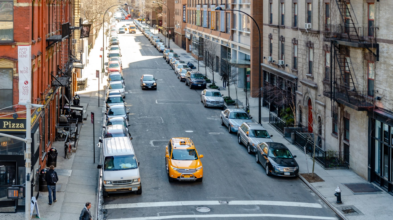 A view of a Brooklyn street lined with parked cars on both sides, representing typical street parking in Brooklyn.